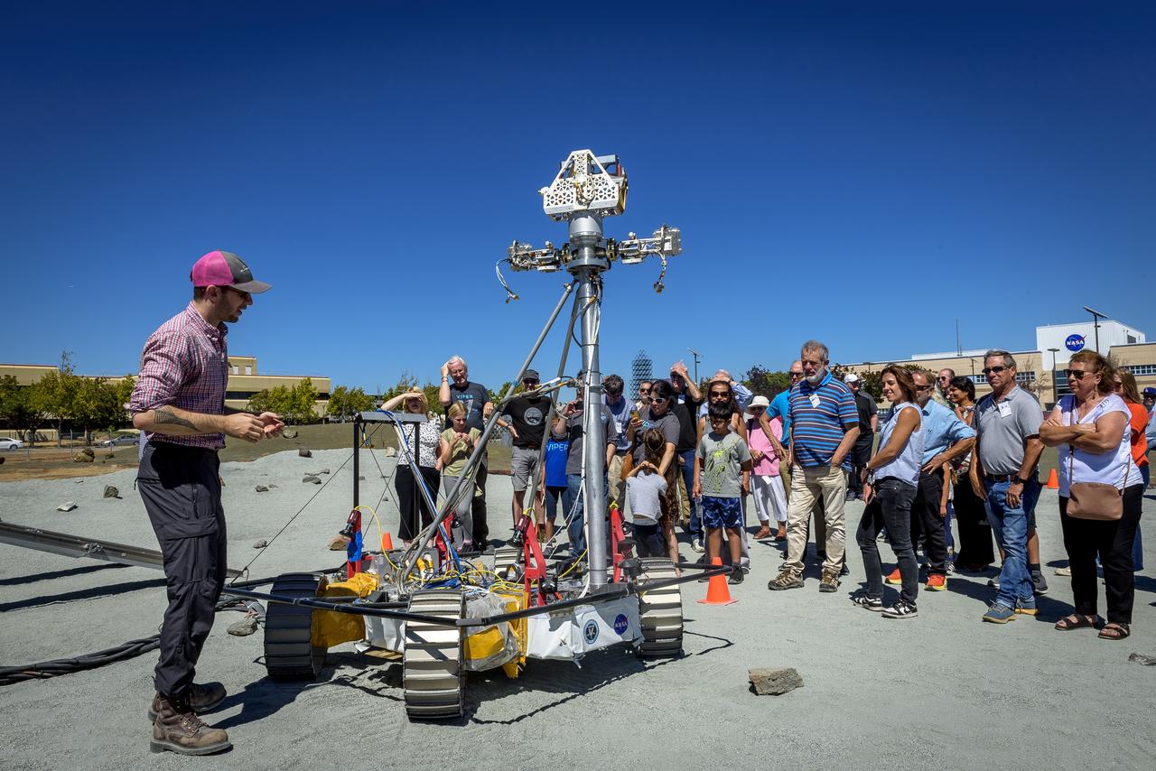 Antoine Tardy explains the operation of the Moon Gravity Representative Unit (MGRU3) at the Roverscape during Family Day for team members of the Volatiles Investigating Polar Exploration Rover (VIPER).  MGRU3 is a weight equivalent mobility and navigation test platform for VIPER. It is used to test, develop and validate the different mobility and navigation techniques and capabilities of the VIPER rover, to safely and efficiently map water at the Moon’s South Pole.