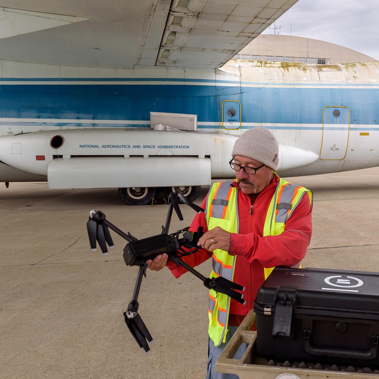 Richard Kolyer unfolds the drone and prepares it for flight around the modified C-141 Kuiper Airborne Observatory, (KAO) (NASA-714).