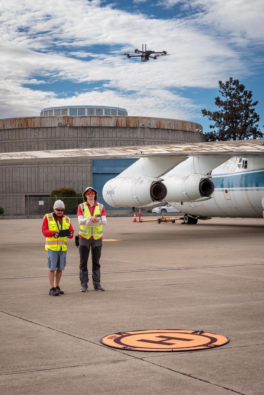 Richard Kolyer, left, with Jonas Jonsson guide the drone to land behind the modified C-141 Kuiper Airborne Observatory, (KAO) (NASA-714), on the N211 apron.