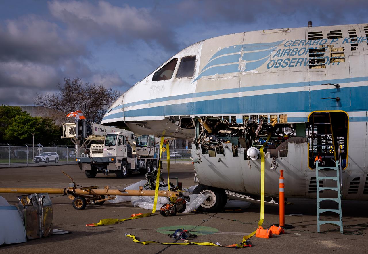 Yellow straps are threaded through the airframe of the modified C-141 Kuiper Airborne Observatory, (KAO) (NASA-714), before removing the cockpit on the N211 apron at Moffett Field, California.
