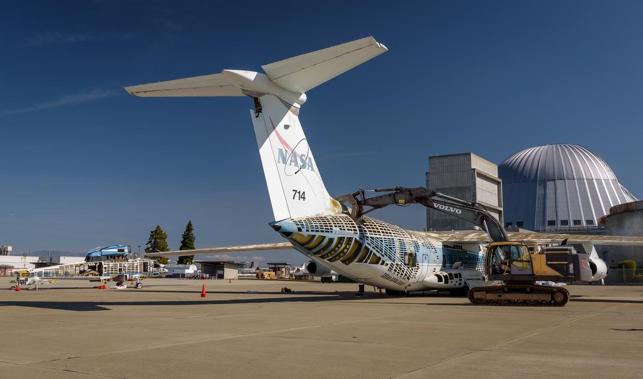A Volvo Crawler Excavator severs the airframe, separating the tail section from the fuselage, of the modified C-141 Kuiper Airborne Observatory, (KAO) (NASA-714), on the N211 apron of Moffett Field, California.