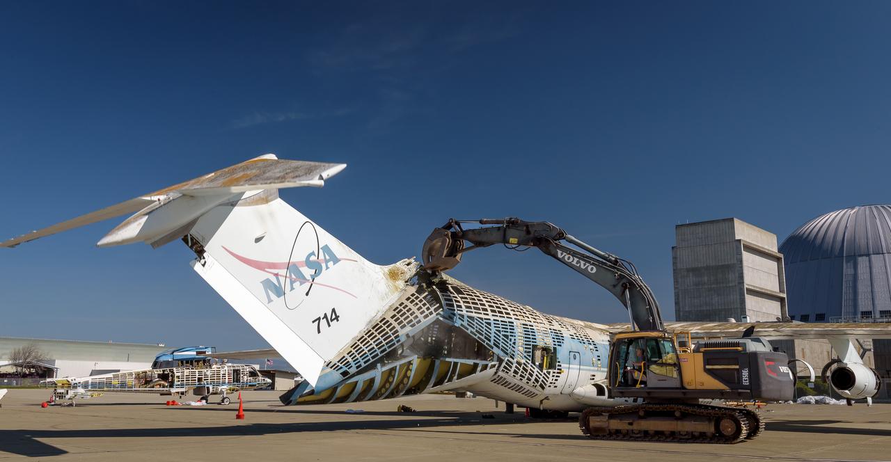 A Volvo Crawler Excavator severs the airframe, separating the tail section from the fuselage, of the modified C-141 Kuiper Airborne Observatory, (KAO) (NASA-714), on the N211 apron of Moffett Field, California.