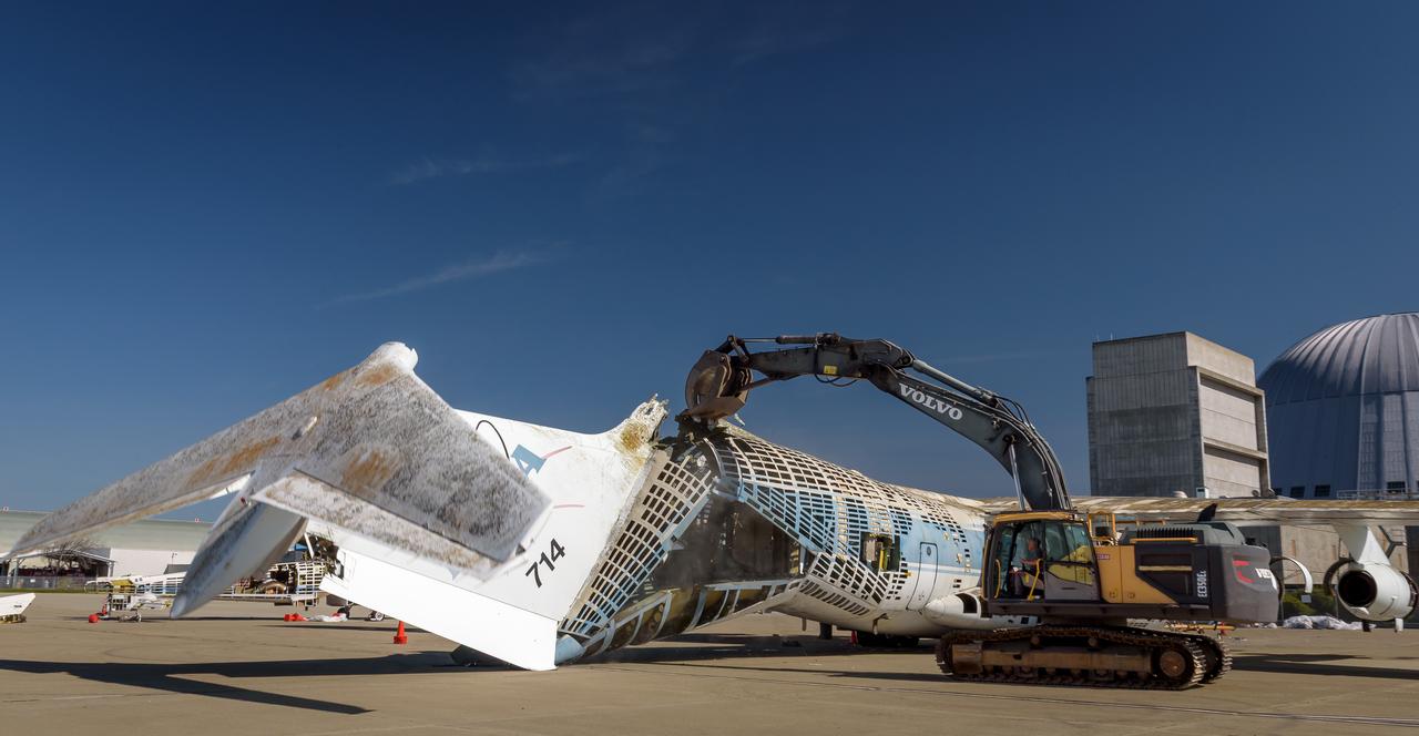 A Volvo Crawler Excavator severs the airframe, separating the tail section from the fuselage, of the modified C-141 Kuiper Airborne Observatory, (KAO) (NASA-714), on the N211 apron of Moffett Field, California.