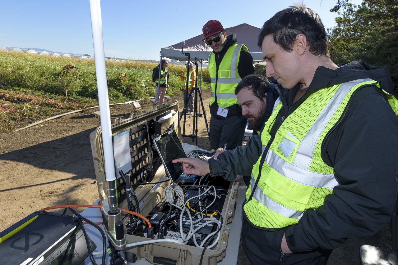 Greg Costedoat, front-right frame, Stefan Blandin, and Charles Walker, left, with the Advanced Capabilities for Emergency Response Operations (ACERO) Portable Airspace Management System (PAMS) case with the equipment stowed at the Monterey Bay Academy Airport near Watsonville, California.