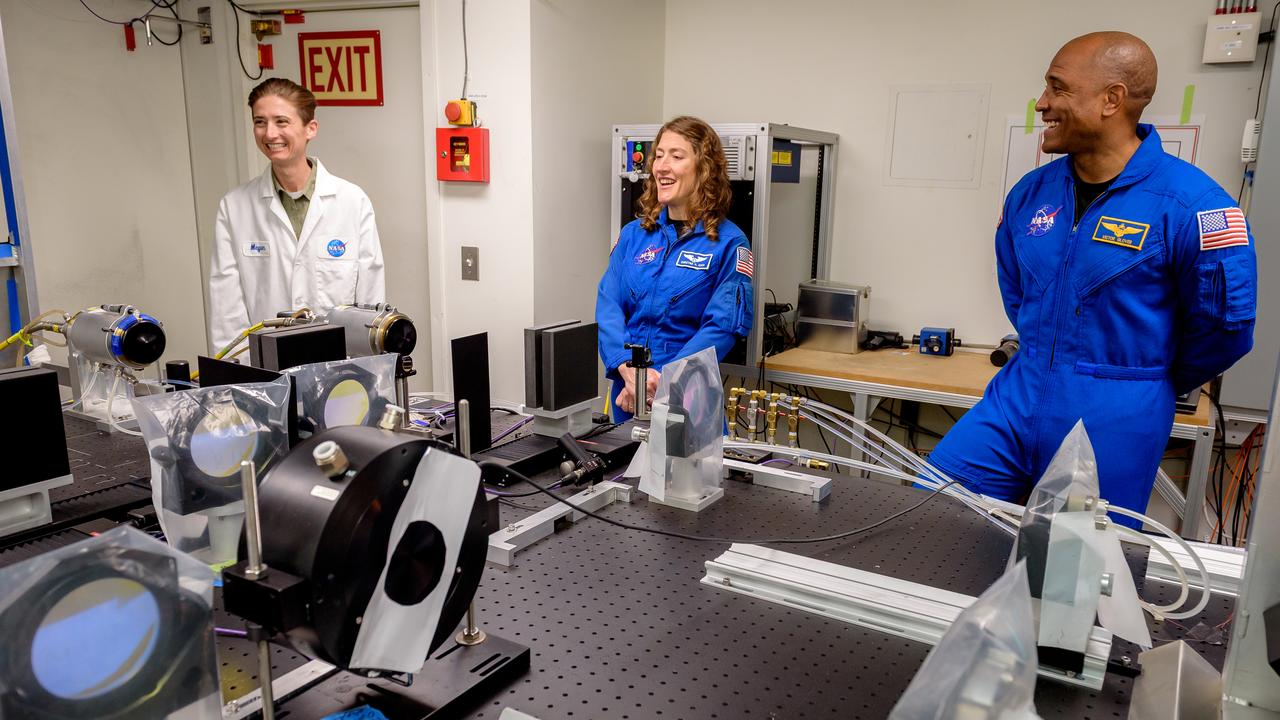 Megan MacDonald, left, leads NASA astronauts Christina Koch and Victor J. Glover, right, on a tour of the Laser Enhanced Arc Jet Facility (LEAF) laboratory, in N238.  The LEAF laser augments the hypersonic shock heating experienced by a test sample during an arc jet test and provides improved test simulation quality by supplying an intense source of optical heating while the arc jet flow provides shock-driven convective heating.