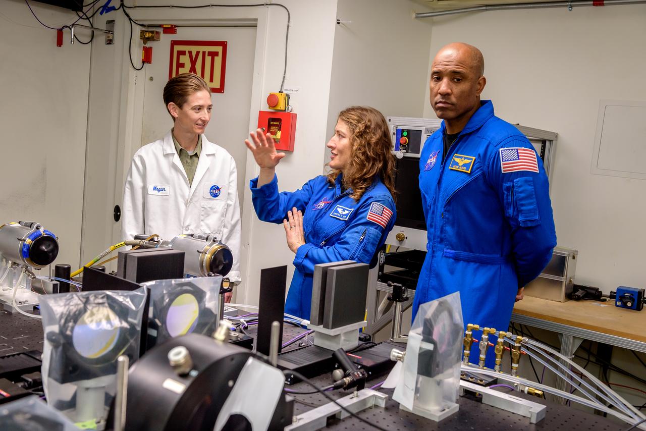 Megan MacDonald, left, leads NASA astronauts Christina Koch and Victor J. Glover, right, on a tour of the Laser Enhanced Arc Jet Facility (LEAF) laboratory, in N238.  The LEAF laser augments the hypersonic shock heating experienced by a test sample during an arc jet test and provides improved test simulation quality by supplying an intense source of optical heating while the arc jet flow provides shock-driven convective heating.