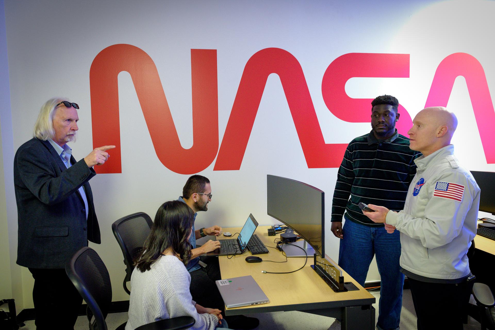 TechEdSat-11 operators Marcus Murbach, left, Daphne Dao and Alejandro Salas, seated, Kwabena Boateng, and Justin Pane, right, in the Ames Multi-Mission Operations Center (MMOC), N240 Annex, Eros control room 162. The team monitors the spacecraft's status during the Exo-Brake “parachute” deployment.   The ExoBrake is a drag device that increases the total surface area of the spacecraft to assist with a quicker deorbit. This maneuver is deployed at the end of mission to satisfy NASA's deorbit requirement and prevent space debris. TechEdSat has spent the last several months coordinating with NASA’s Conjunction Assessment Risk Analysis (CARA) team to ensure the spacecraft can safely deploy the ExoBrake without colliding into any other objects.