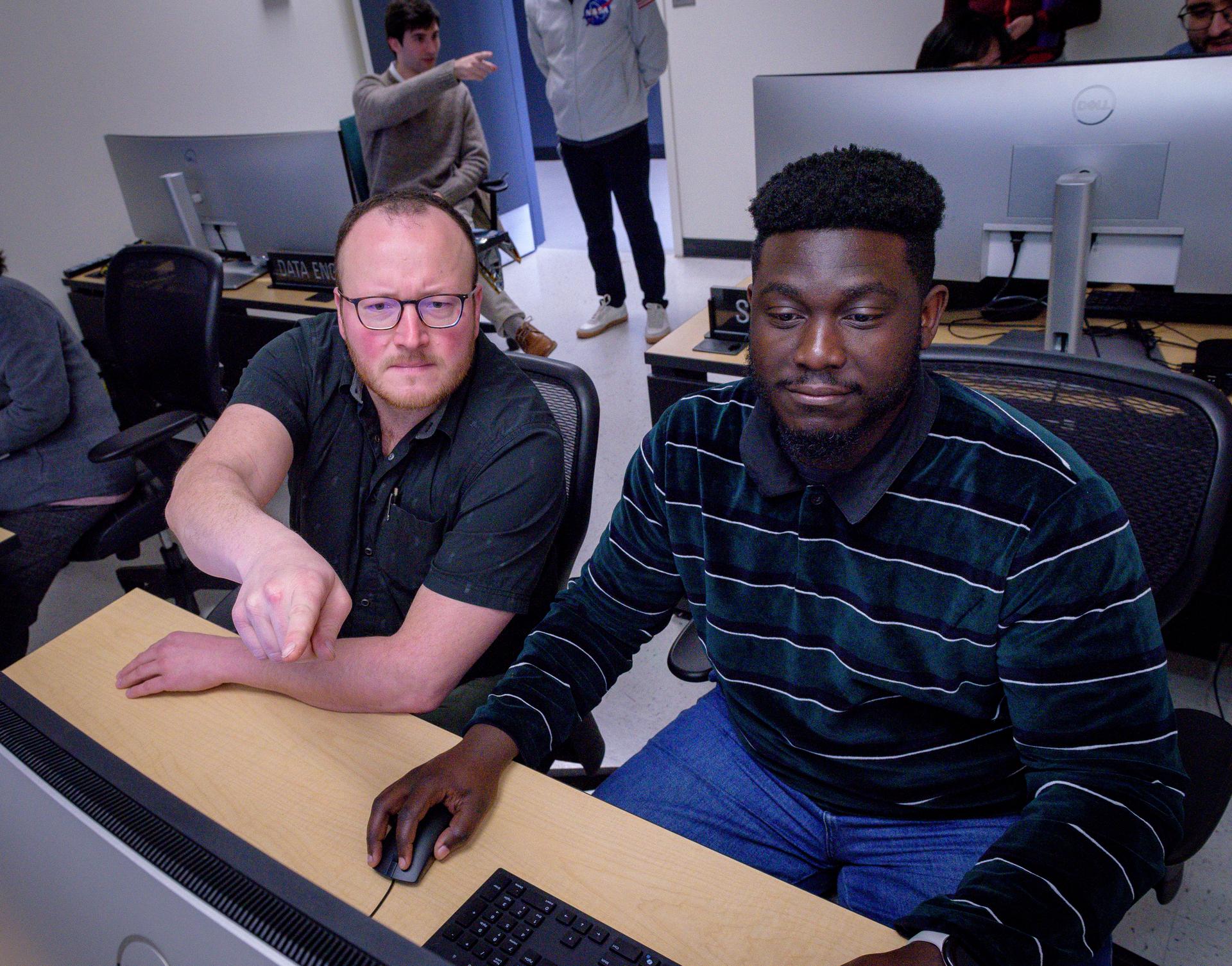 TechEdSat-11 operators Luke Idziak, left, and Kwabena Boateng, in the Ames Multi-Mission Operations Center (MMOC), N240 Annex, Eros control room 162. The operators monitor the spacecraft's status during the Exo-Brake “parachute” deployment.   The ExoBrake is a drag device that increases the total surface area of the spacecraft to assist with a quicker deorbit. This maneuver is deployed at the end of mission to satisfy NASA's deorbit requirement and prevent space debris. TechEdSat has spent the last several months coordinating with NASA’s Conjunction Assessment Risk Analysis (CARA) team to ensure the spacecraft can safely deploy the ExoBrake without colliding into any other objects.