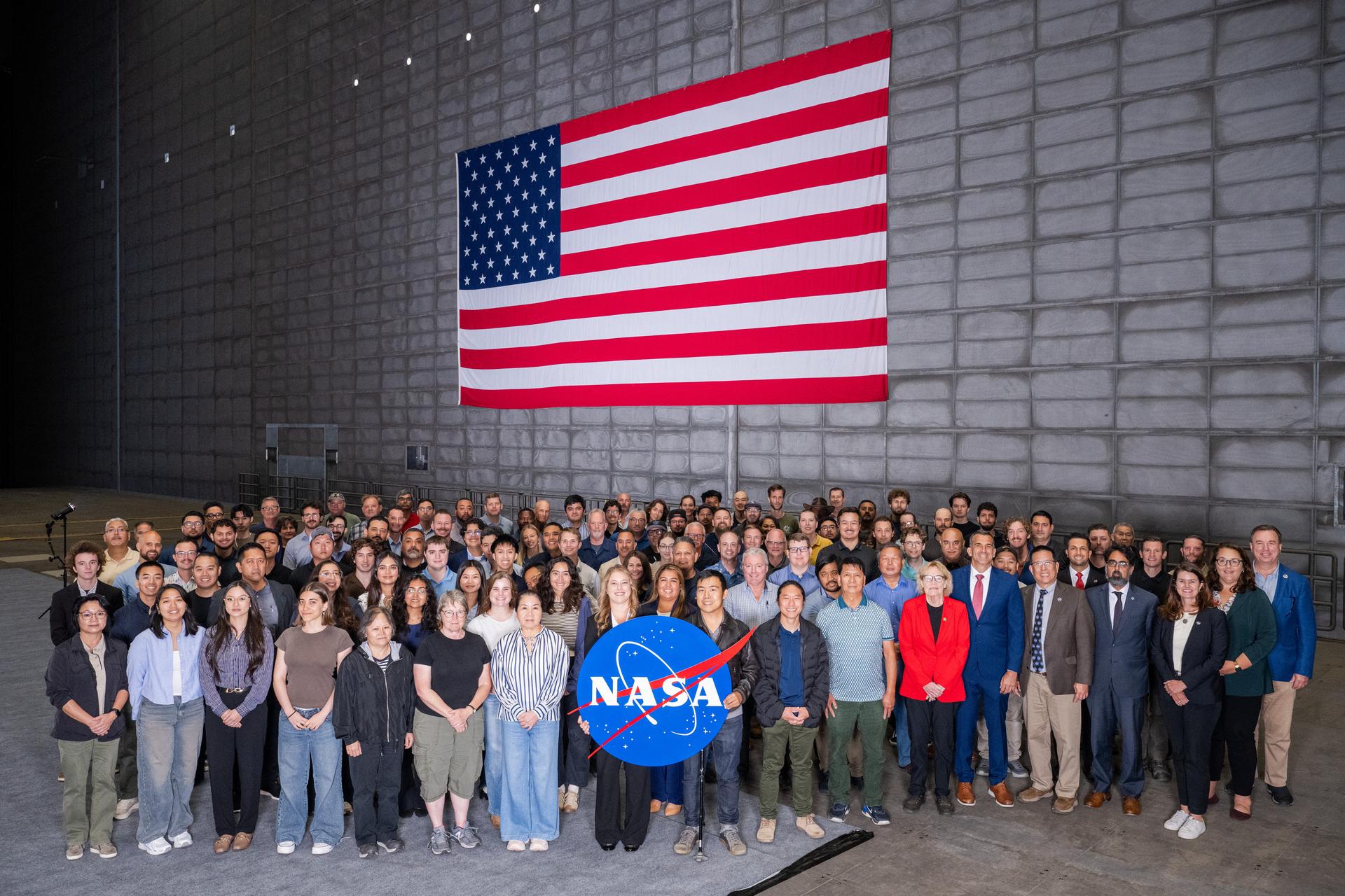 Group photo of the new civil servants and guests with NASA and Ames Center leadership after the NASA Civil Servant Swearing-in Ceremony in the National Full-Scale Aerodynamics Complex (NFAC) 80-by-120-foot test section, N221.