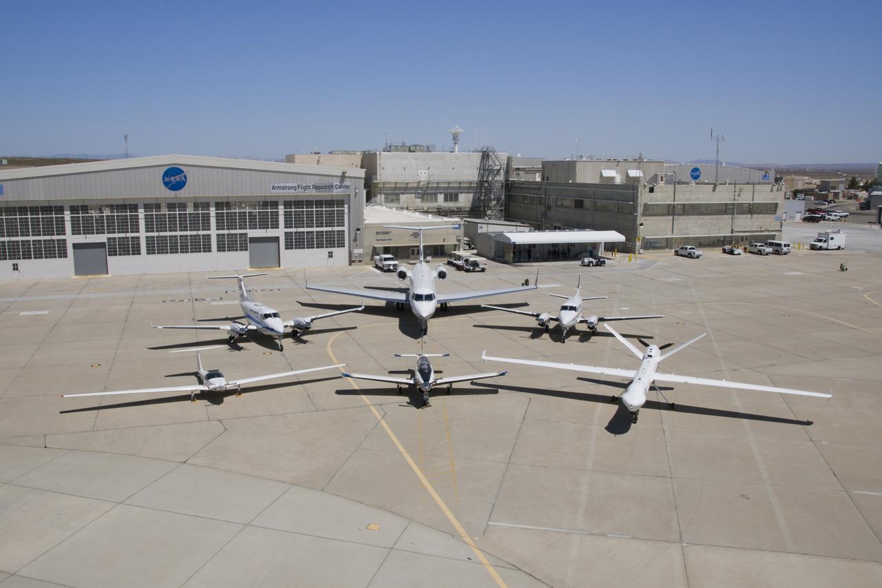 NASA’s Ikhana remotely piloted aircraft (front-right) is situated near NASA Armstrong Flight Research Center’s Hangar 4802 after an Unmanned Aircraft Systems Integration into the National Airspace System Flight Test Series 4 flight, along with five flight “intruders.” These intruders, which include NASA’s TG-14 (front-left), T-34C (front-center), B-200 King Air (back-left), Gulfstream-III (back-center) and a Honeywell C-90 King Air (back-right), fly within a pre-determined distance to Ikhana to test Detect-and-Avoid technology during research flights.