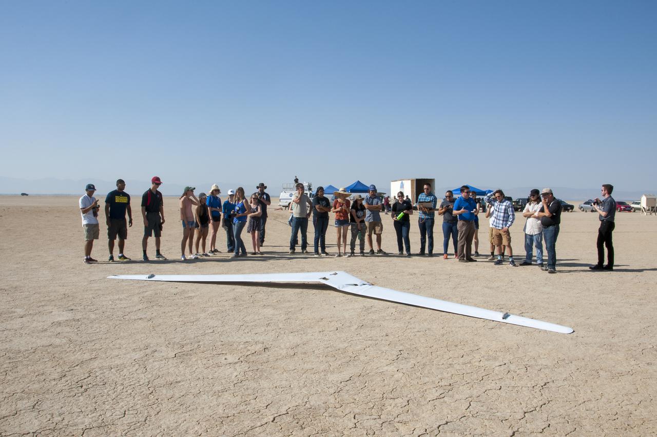 Student interns and NASA personnel cluster in front of PRANDTL-D No. 3 following a crash on Rosamond Dry Lake. The radio-controlled glider was built to validate a new spanload.