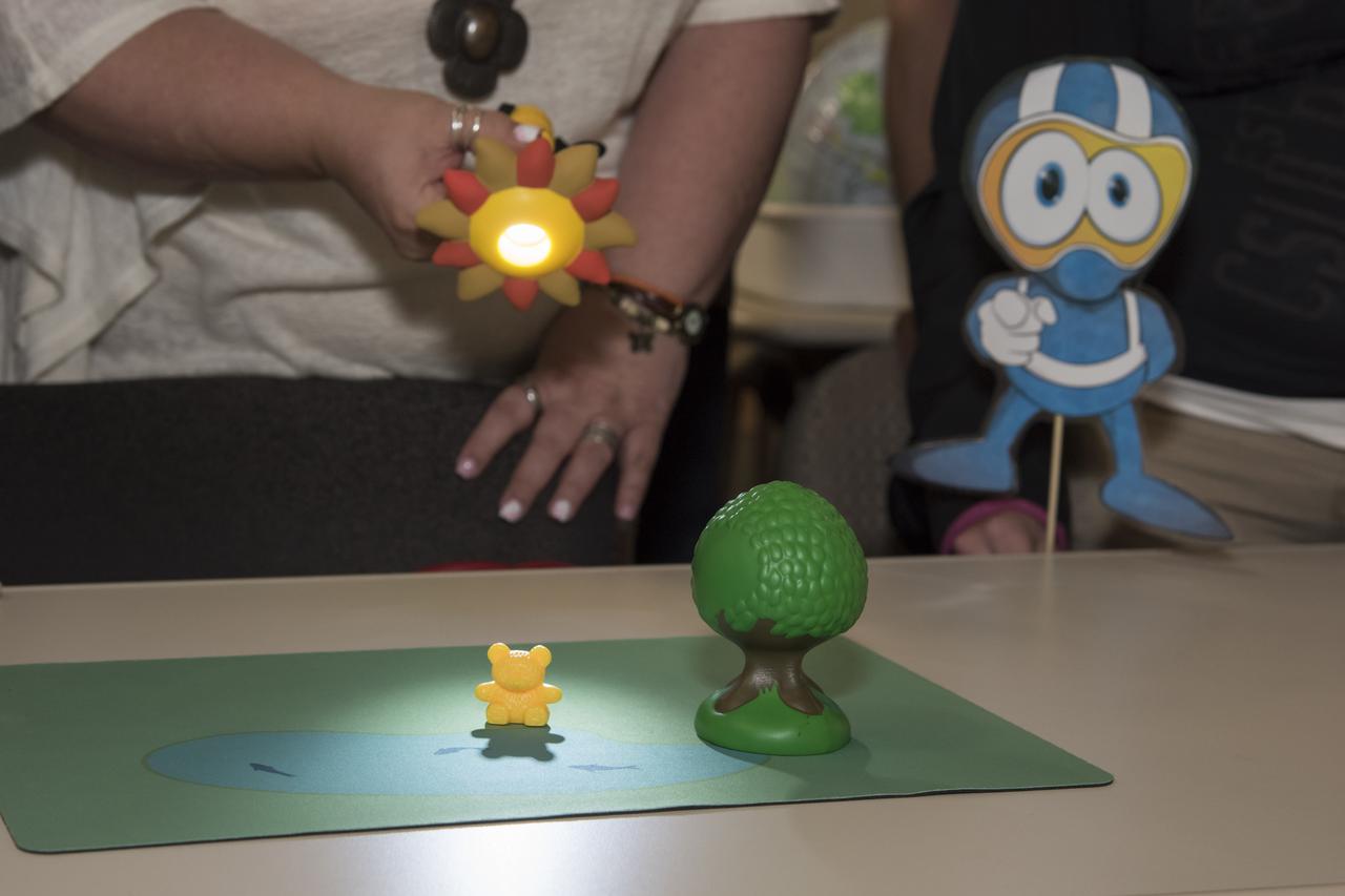 Educators shine a flashlight onto a toy bear to simulate the physics behind solar eclipses.