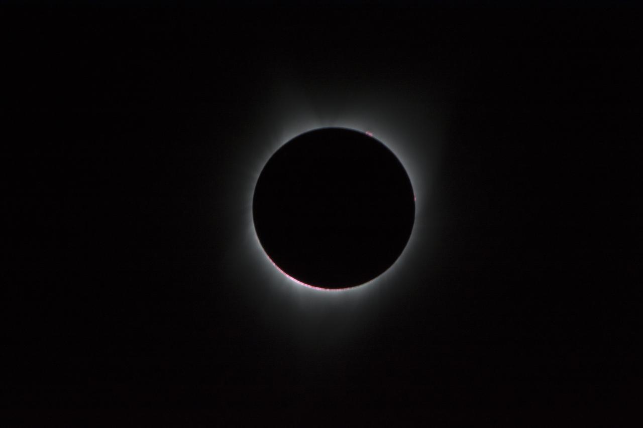 During the total solar eclipse, the Sun’s corona, only visible during the total eclipse, is shown as a crown of white flares from the surface. The red spots called Bailey's beads occurs where the moon grazes by the Sun and the rugged lunar limb topography allows beads of sunlight to shine through in some areas as photographed from NASA Armstrong’s Gulfstream III. Photo Credit: (NASA/Carla Thomas)