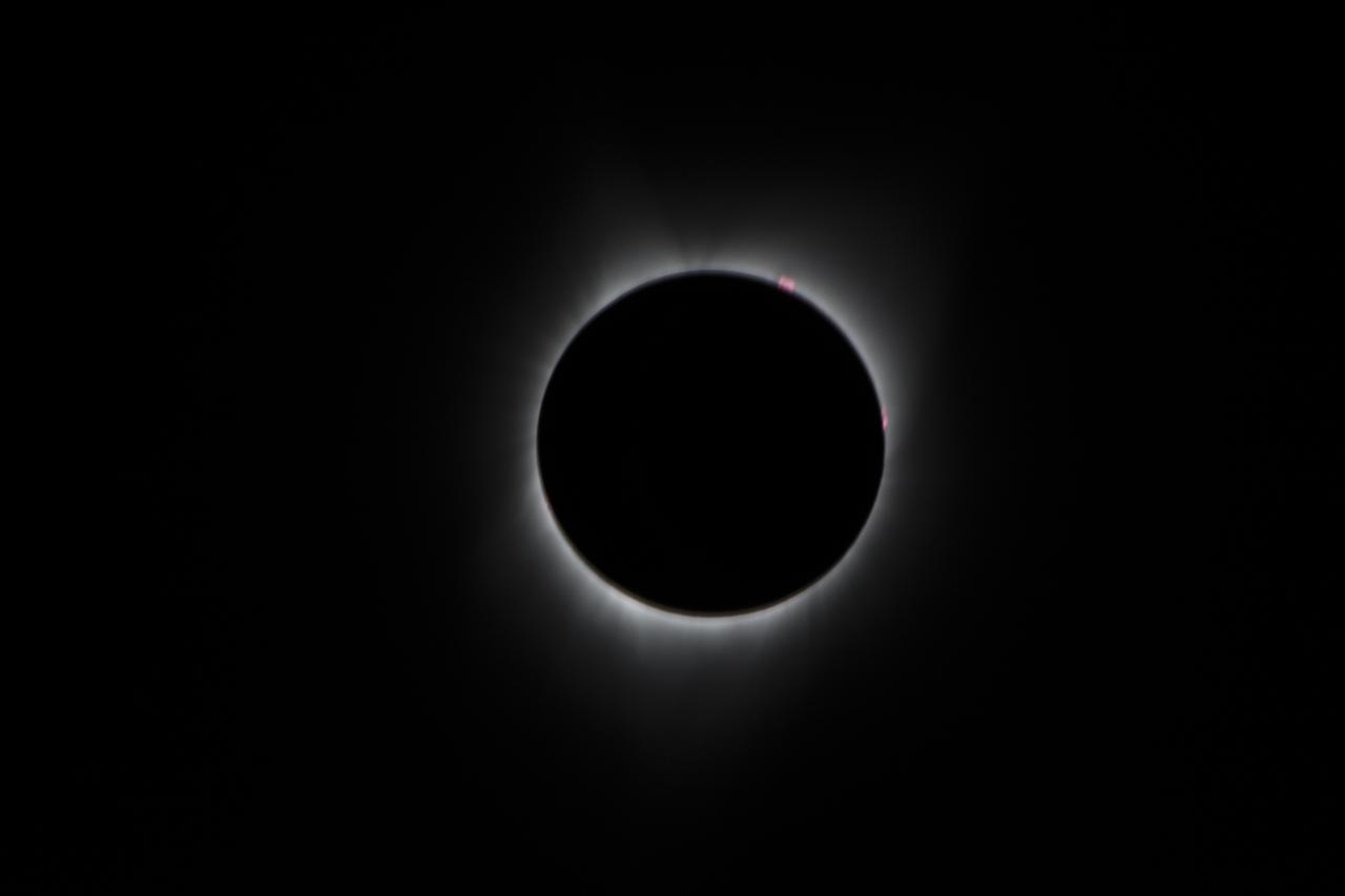 During the total solar eclipse, the Sun’s corona, only visible during the total eclipse, is shown as a crown of white flares from the surface. The red spots called Bailey's beads occurs where the moon grazes by the Sun and the rugged lunar limb topography allows beads of sunlight to shine through in some areas as photographed from NASA Armstrong’s Gulfstream III. Photo Credit: (NASA/Carla Thomas)