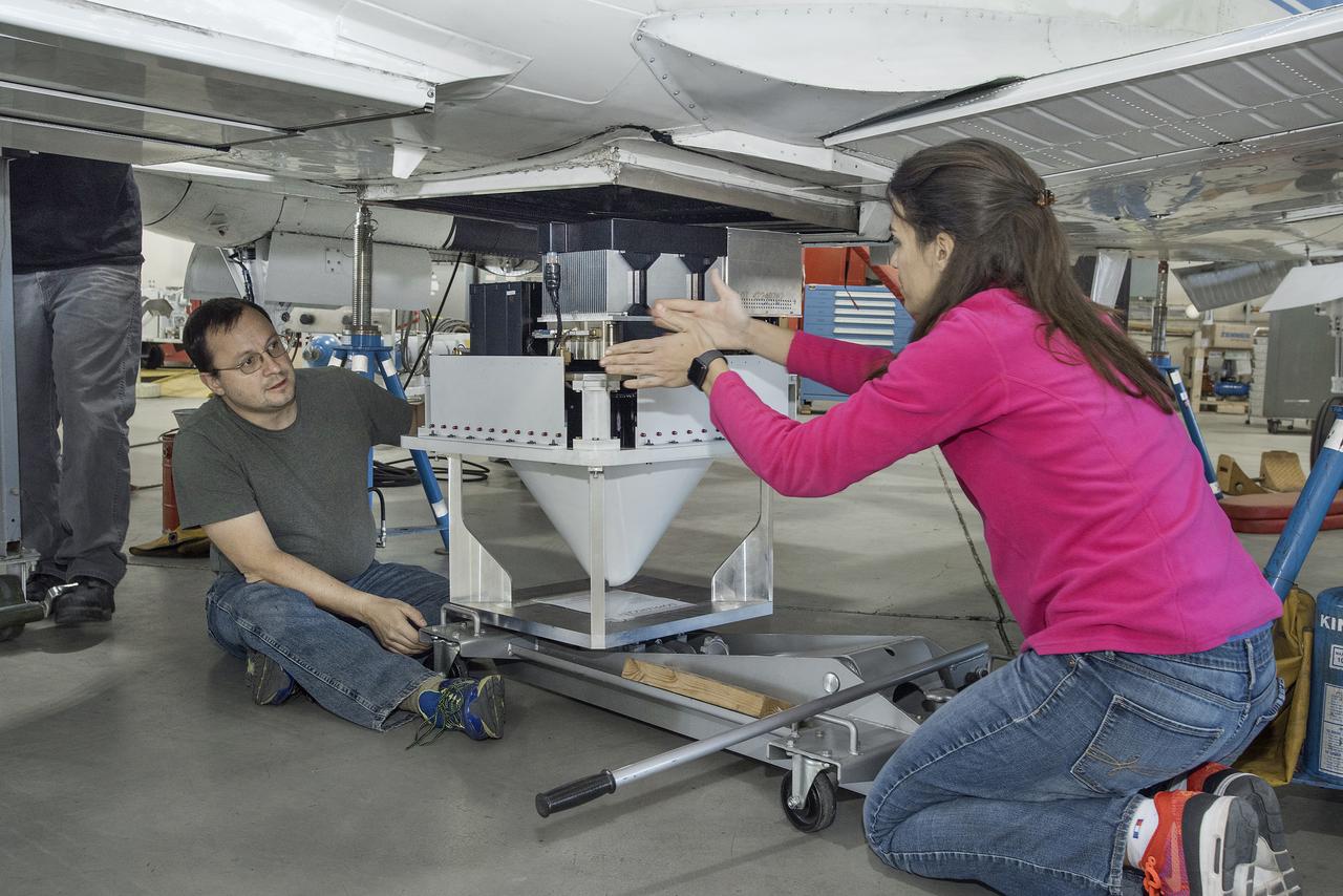Engineers Raquel Rodriguez Monje and Fabien Nicaise discuss placement of the DopplerScatt radar instrument on the NASA B200 before its final installation onto the aircraft’s fuselage.