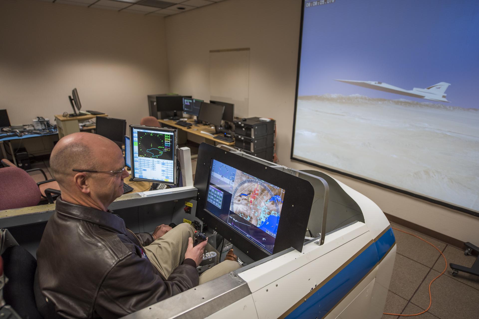 NASA test pilot Nils Larson operates the X-59 flight simulator at Armstrong Flight Research Center, evaluating sonic boom prediction software.