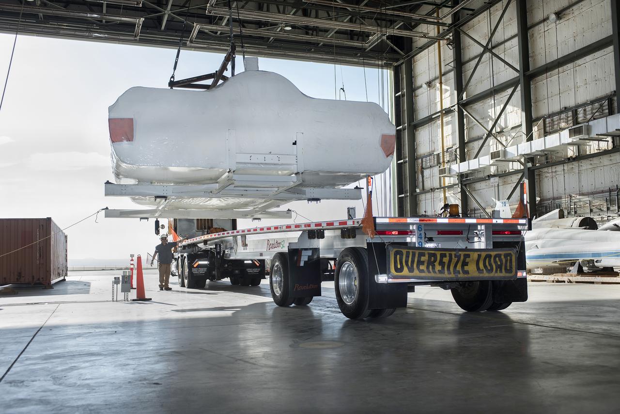 SNC Dream Chaser is lifted on to a truck in NASA Armstrong’s historic space shuttle hangar where the spacecraft stayed as it was being prepared for testing and flights. Dream Chaser is in Colorado at a SNC facility.