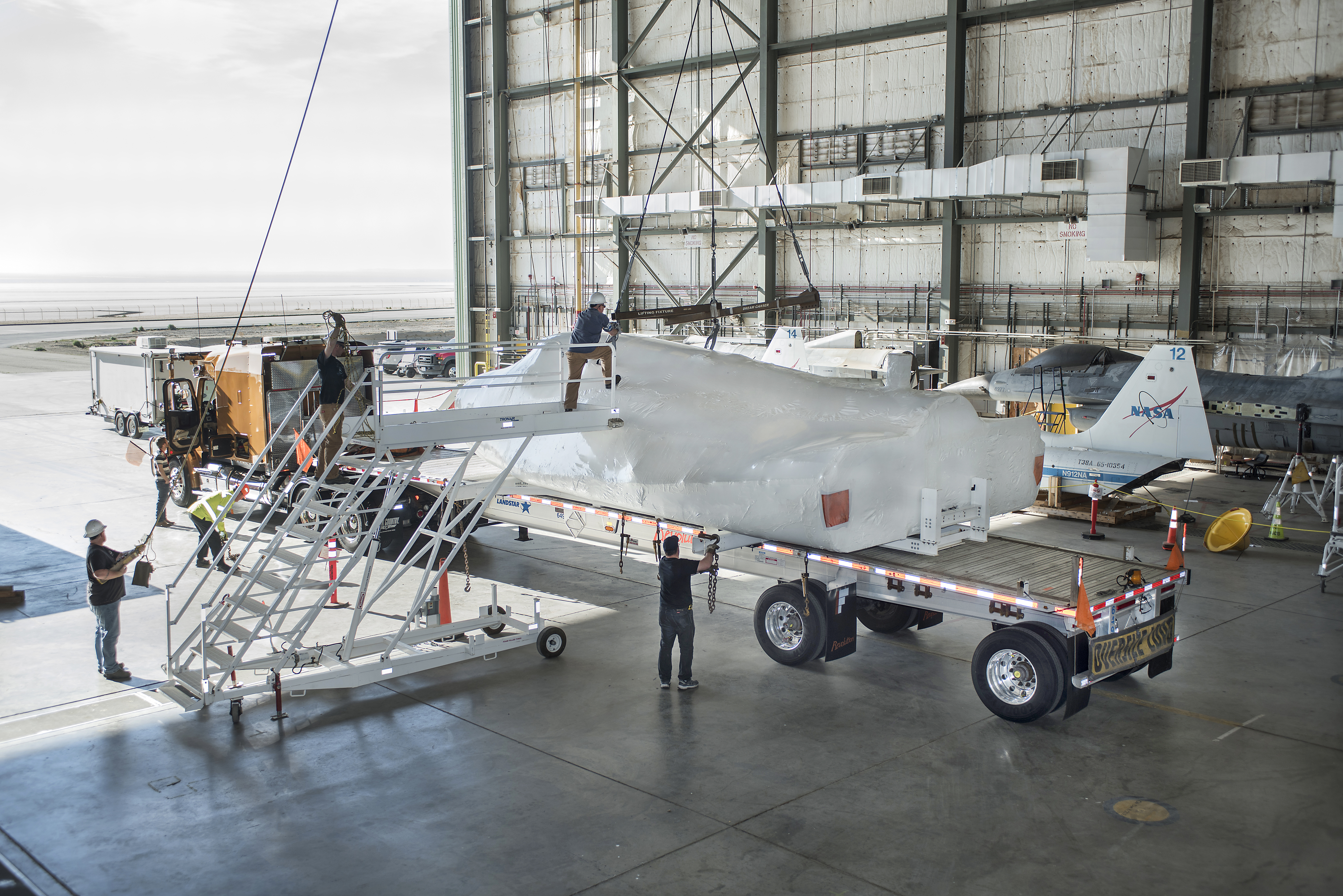 SNC Dream Chaser is in NASA Armstrong, previously known as space shuttle, hangar being loaded on truck for its departure from the center heading to SNC in Colorado.