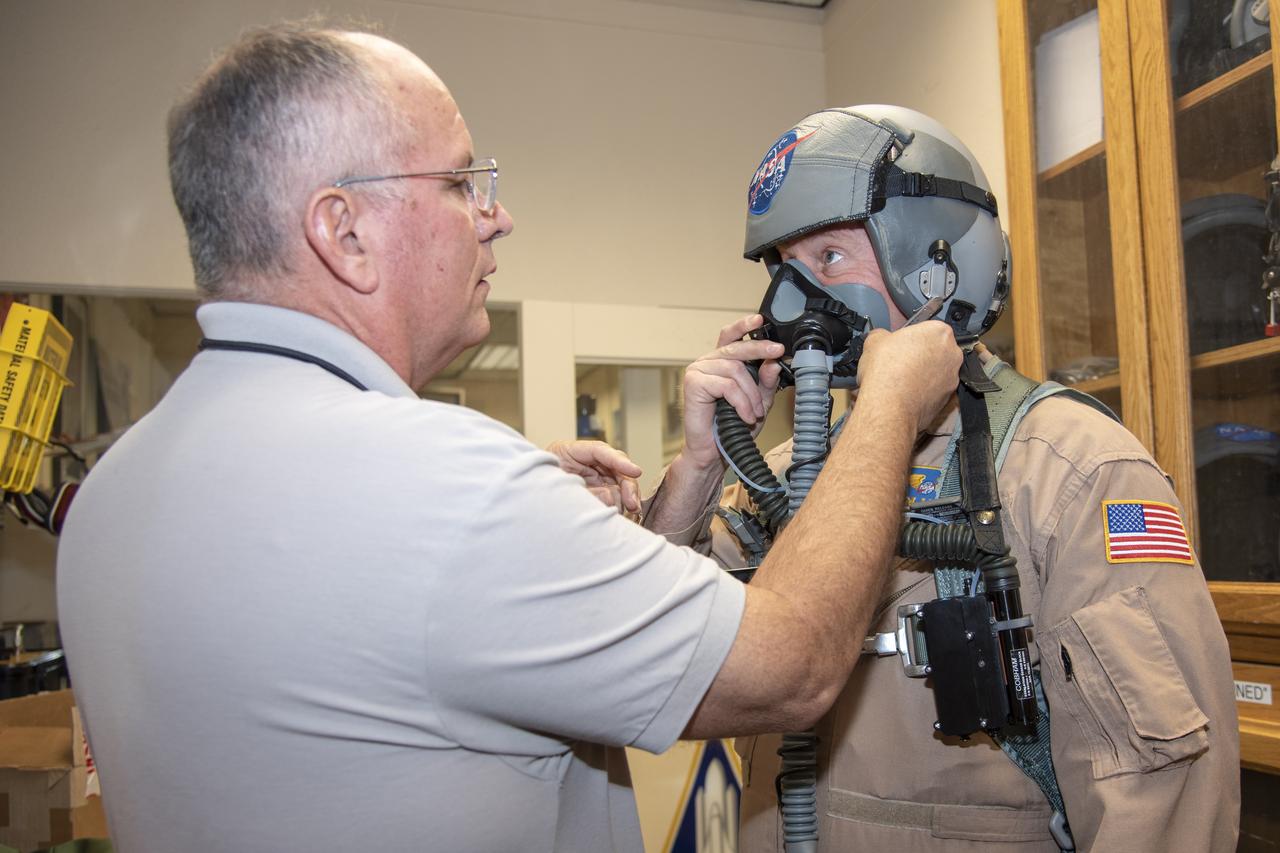 NASA pilot Jim Less is assisted by life support as he is fitted with a Cobham designed VigiLOX pilot oxygen monitoring system. VigiLOX is a sensing system that is attached to a pilot's existing gear to capture real-time physiological, breathing gas and cockpit environmental data.
