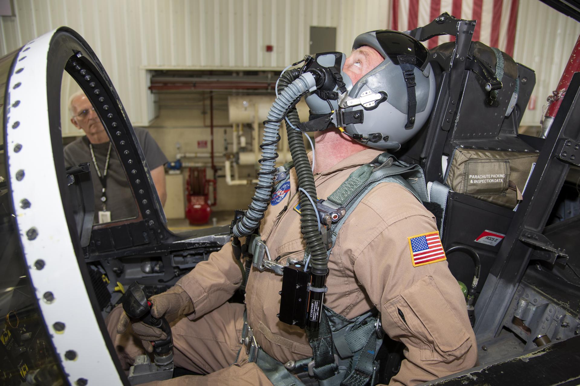 A pilot in a cockpit wears a suit designed to monitor breathing.