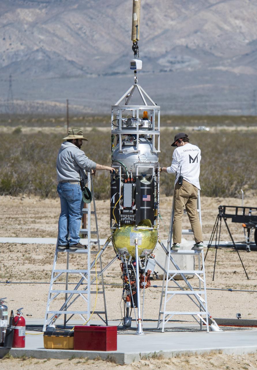 Masten Space Systems’ technicians prepare their Xodiac rocket to flight test Honeybee Robotics pneumatic sampler collection system, PlanetVac, in Mojave Desert.