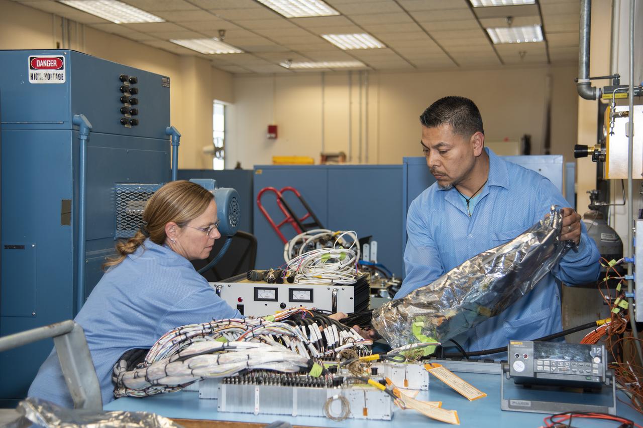 April Torres and Angelo De La Rosa remove wire harnesses for signal input for the Orion AA-2 vehicle from electrostatic discharge protective covers at NASA’s Armstrong Flight Research Center in California. The AA-2 test article is scheduled for a flight in 2019.