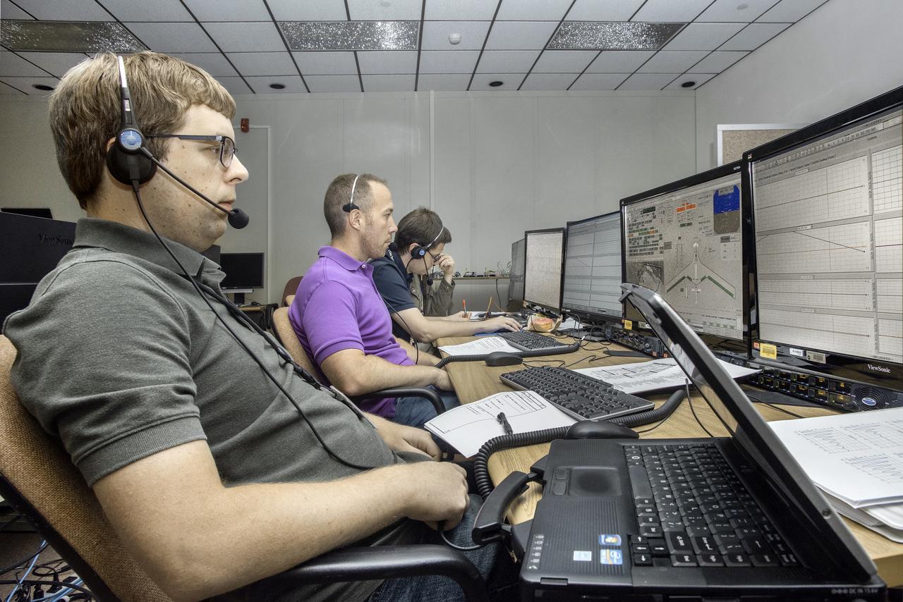 Jake Schaefer, left, looks over control information on a monitor in front of him for the X-56A before flight. Next to him are Matt Boucher, Jeff Ouellette and Peter Suh.