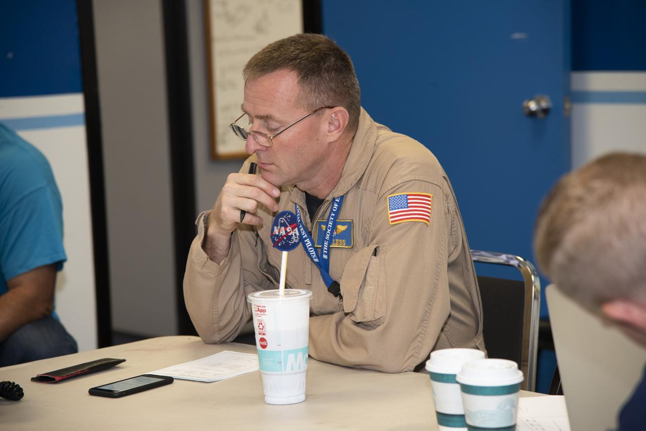 The flight operations crew for NASA’s QSF18 flight series debriefs following a flight with the F/A-18 research aircraft. The flight included a quiet supersonic dive maneuver at high altitudes off the coast to produce a sonic boom out over the ocean, with the intention of producing quieter “thumps” on land.