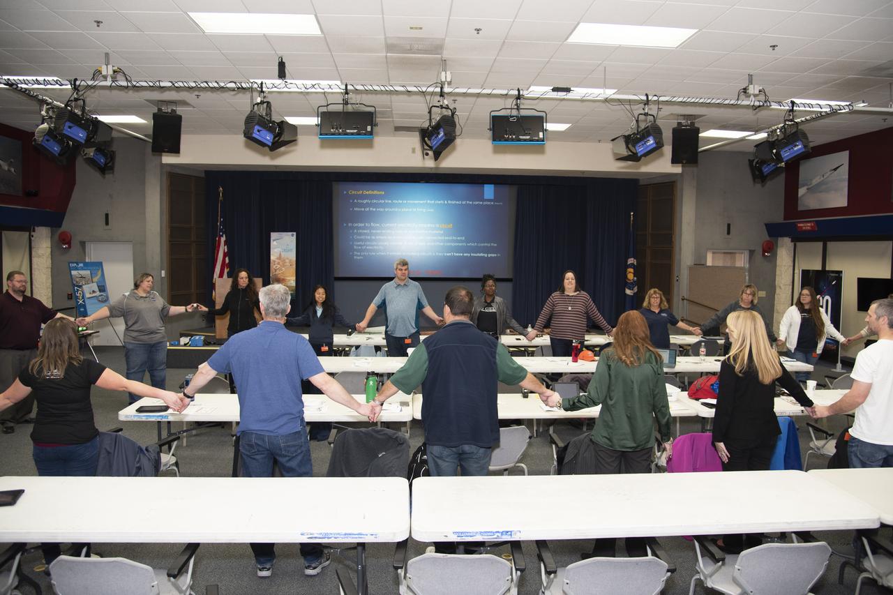 Barbara Buckner, NASA Armstrong's educator professional development specialist, leads a group exercise to form a human circuit to power an electric ball.