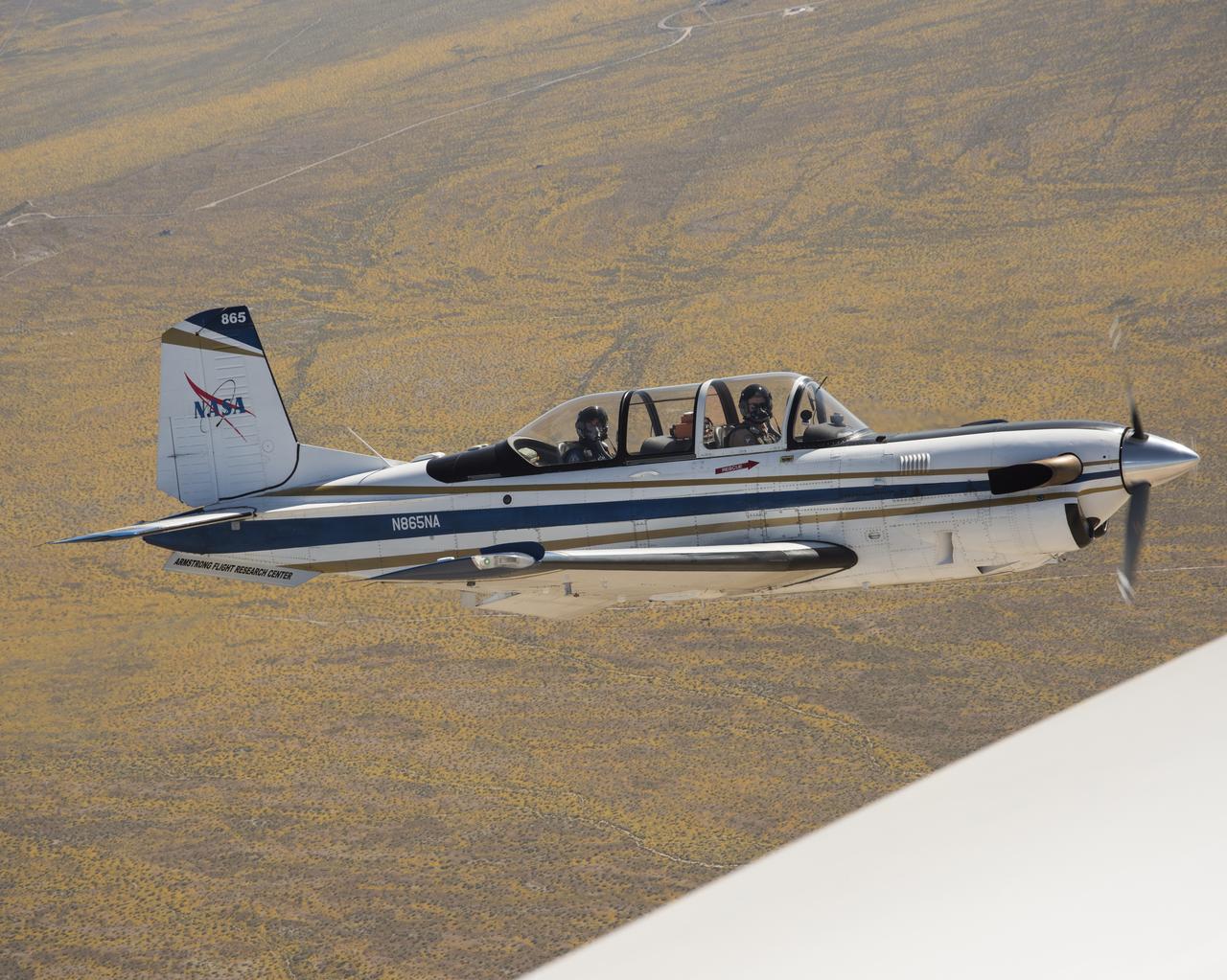 NASA’s T-34 aircraft flown from the agency’s Armstrong Flight Research Center aims the plane toward Southern California’s Antelope Valley Poppy Reserve flying over yellow wildflowers. The aircraft was flown from the agency’s Armstrong Flight Research Center.