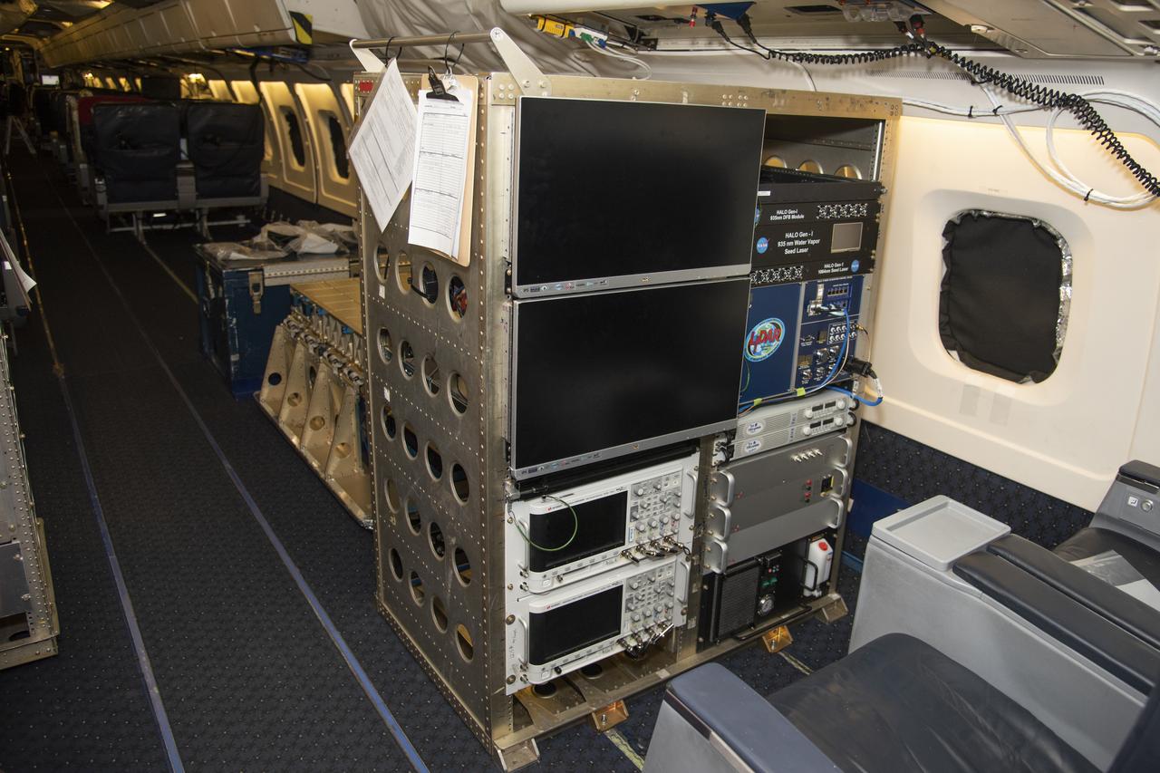 The High Altitude Lidar Observatory (HALO) system electronics and diagnostic tools are integrated onto the DC-8 airborne science laboratory at NASA Armstrong Flight Research Center in Edwards, California. The lidar system control electronics are on the right hand side of the rack. The large monitors on the left are used to display real-time images of water vapor and aerosol profiles, which are used by the science team to guide in-flight decisions and navigation. The compact HALO instrument head can be seen directly behind the electronics rack.