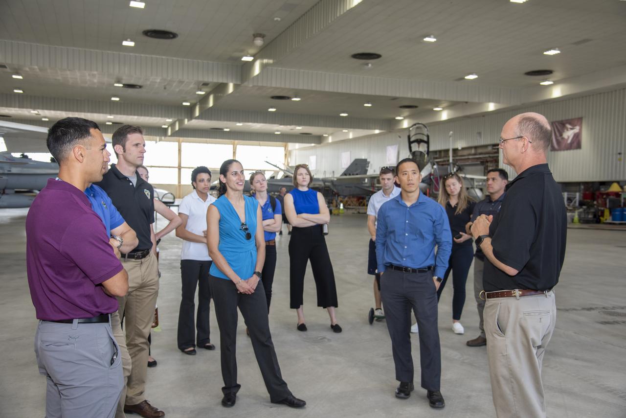 NASA's 2017 astronaut candidates toured aircraft hangar at Armstrong Flight Research Center, in Southern California. On the right, NASA's, X-59 pilot Nils Larsen, briefs the astronauts as they look at Armstrong's fleet of supersonic research support aircraft, including the F-15, which will fly in tandem with the X-59 QueSST during early flight test stages, and the F-18, which is conducting supersonic research in support of the overall mission.