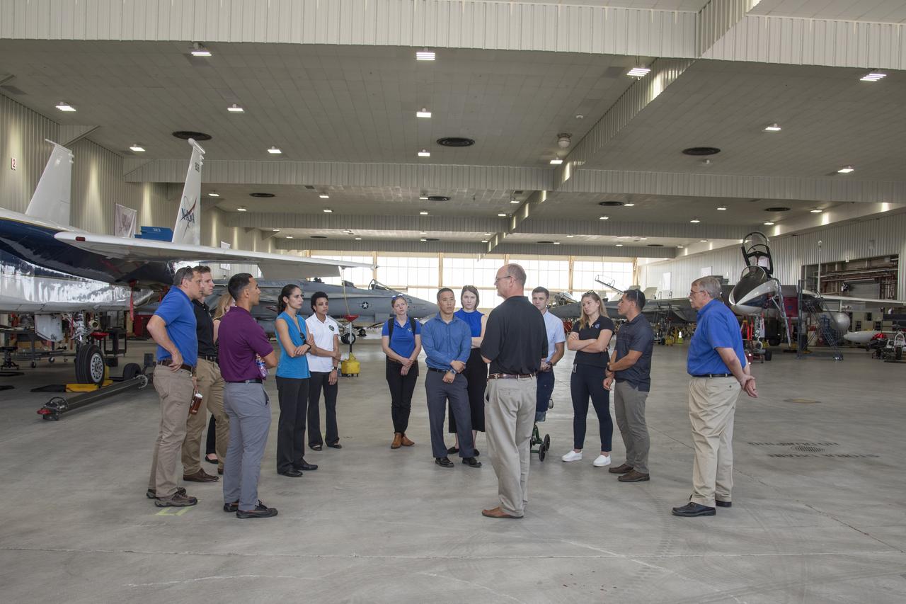 NASA's 2017 astronaut candidates toured aircraft hangar at Armstrong Flight Research Center, in Southern California. On the right, NASA's, X-59 pilot Nils Larsen, briefs the astronauts as they look at Armstrong's fleet of supersonic research support aircraft, including the F-15, which will fly in tandem with the X-59 QueSST during early flight test stages, and the F-18, which is conducting supersonic research in support of the overall mission.