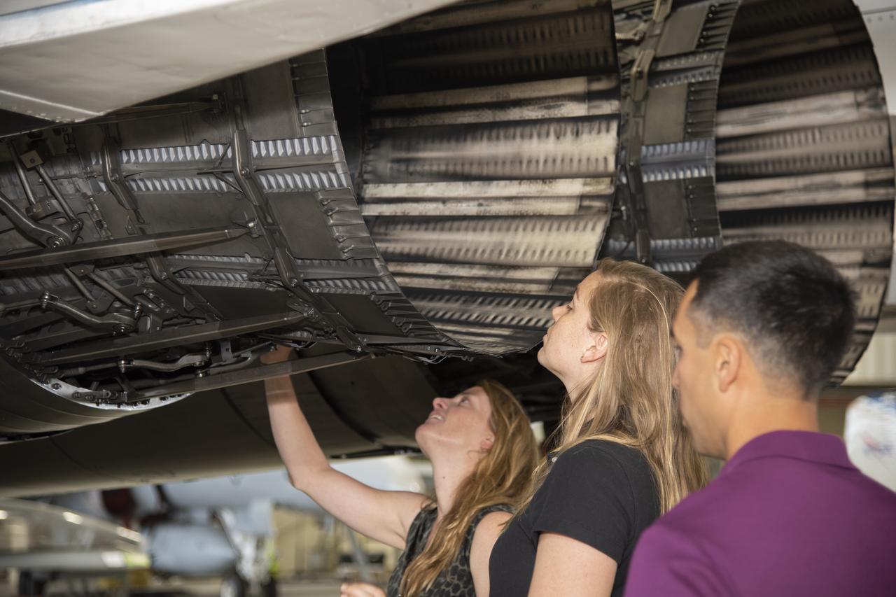 NASA's 2017 astronaut candidates toured aircraft hangar at Armstrong Flight Research Center, in Southern California where (L to R) Loral O'Hara, Jenni Sidey-Gibbons and Raja Chari look inside the engine nozzle of an F-15 jet. The F-15 will fly in tandem with the X-59 QueSST during early flight test stages for the X-59 development.