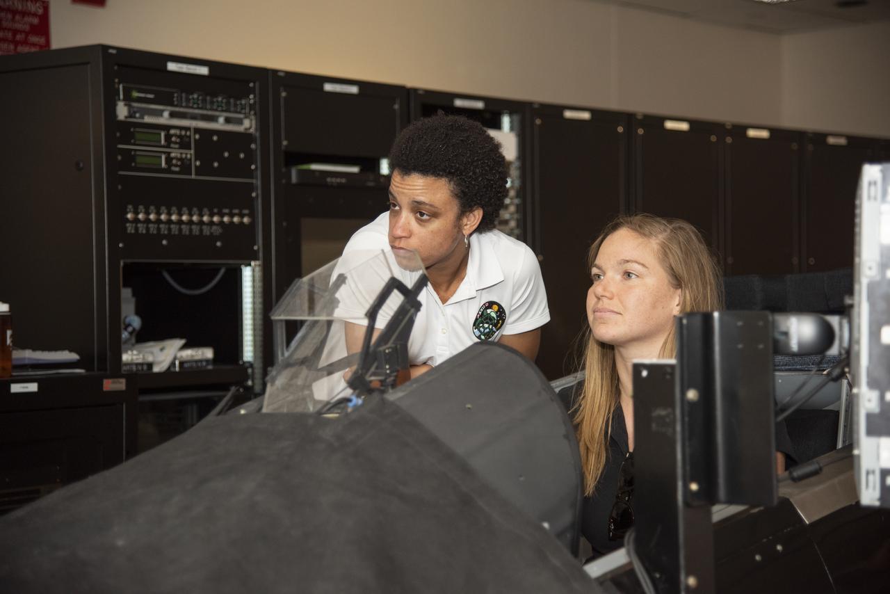 NASA's 2017 astronaut candidates (L to R) Jessica Watkins and Jenni Sidey-Gibbons practice flying in an F-18 aircraft cockpit simulator at Armstrong Flight Research Center, in Southern California. The F-18's are flown for research support and pilot proficiency. Currently, the F-18's are being used to conduct supersonic research in support of the X-59 QueSST overall mission.
