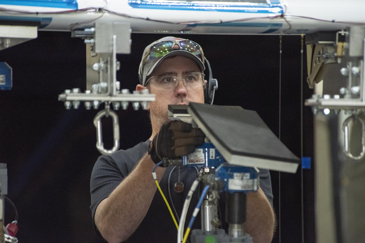 Ray Sadler adjusts hydraulic actuators with pads to the wing of the X-57 distributed electric aircraft wing at NASA's Armstrong Flight Research Center in California. Tests increased confidence in the wing's durability and calibrated installed strain gauges for inflight load monitoring of the wing.