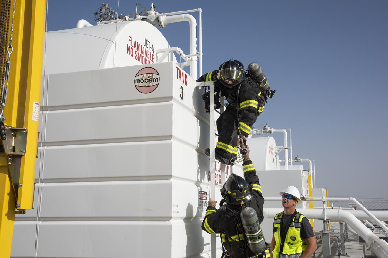 Air Force Plant 42 Fire Department responder Alfonzo Ortega, bottom, hands Doug Mendez a gas meter to test the air in a confined space during an exercise at NASA Armstrong Flight Research Center's Building 703 in Palmdale, California. Dale McCoy, Armstrong confined space co-program manager, observers.