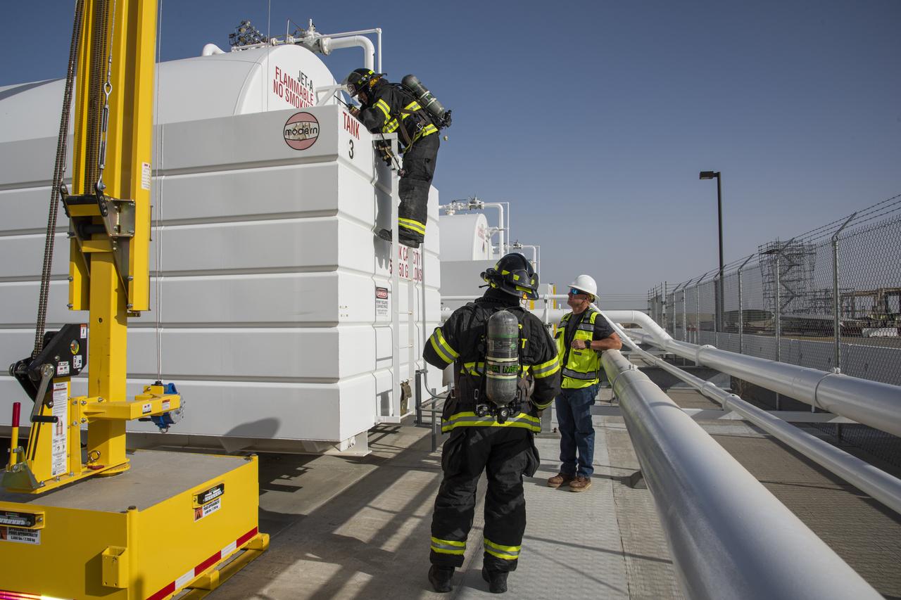 Air Force Plant 42 Fire Department responders Doug Mendez and Alfonzo Ortega test the air in a confined space with a gas meter during an exercise at NASA Armstrong Flight Research Center's Building 703 in Palmdale, California. Dale McCoy, Armstrong confined space co-program manager, observers.