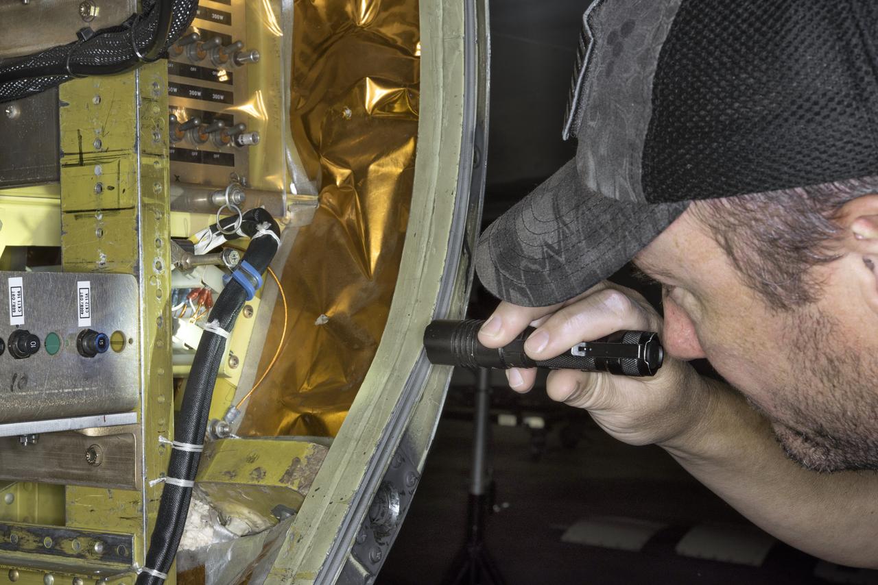A ground crewman at NASA’s Armstrong Flight Research Center in Palmdale, CA inspects the forward panel on the mid-body section of NASA’s ER2’s wingpod. The crew is preparing to fly the air-LUSI instrument aboard the ER2 to measure the Moon.