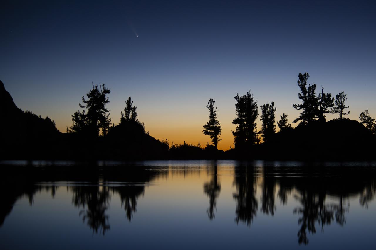 An image of the Comet C/2020 F3 NEOWISE (Comet NEOWISE) captured above the tree line of Lone Pine Lake, located on the Mount Whitney Trail in the Eastern Sierra Nevada Mountains in California. The photo was taken at 4:59 am on July 14, 2020. Visiting from the distant parts of the solar system, it’s characterized by a glowing tail and is visible during the month of July. The comet returns  in 6,800 years. 