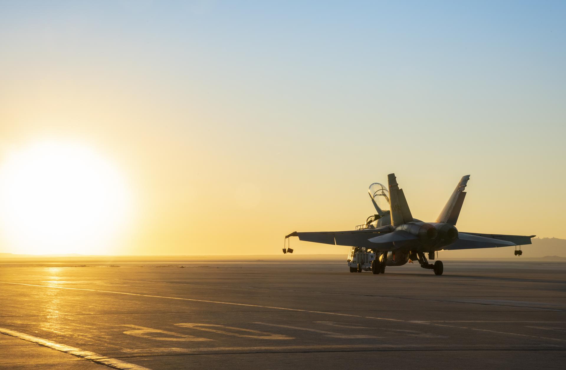 An aircraft is towed at sunset.