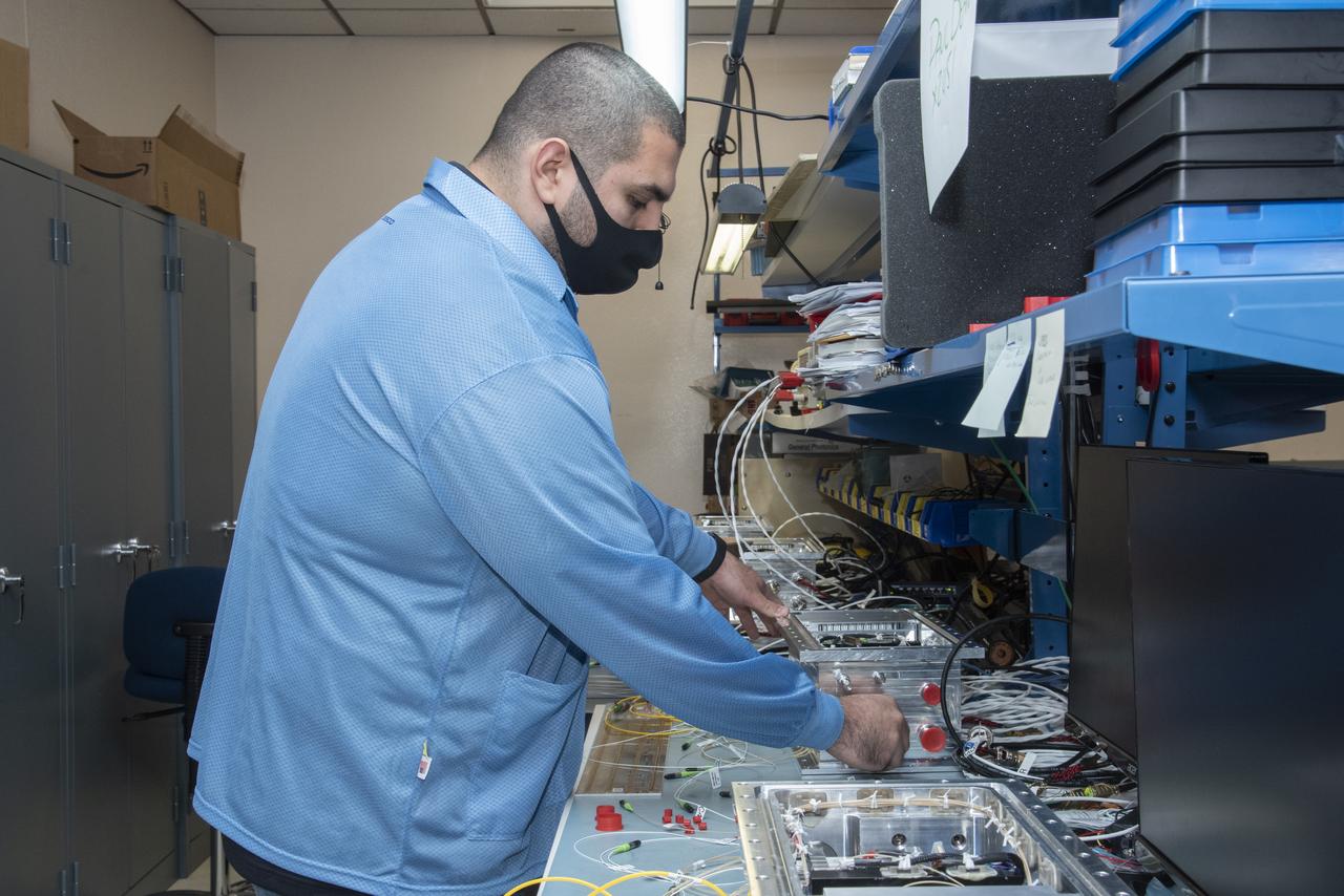 NASA research engineer Jonathan Lopez works on preparing a Compact Fiber Optic Sensing System unit, also known as a FOSS Rocket Box, which was developed at NASA's Armstrong Flight Research Center in California. The unit is a new variant of aircraft technology that researchers have advanced to withstand the harsh environments of a rocket launch and space travel.