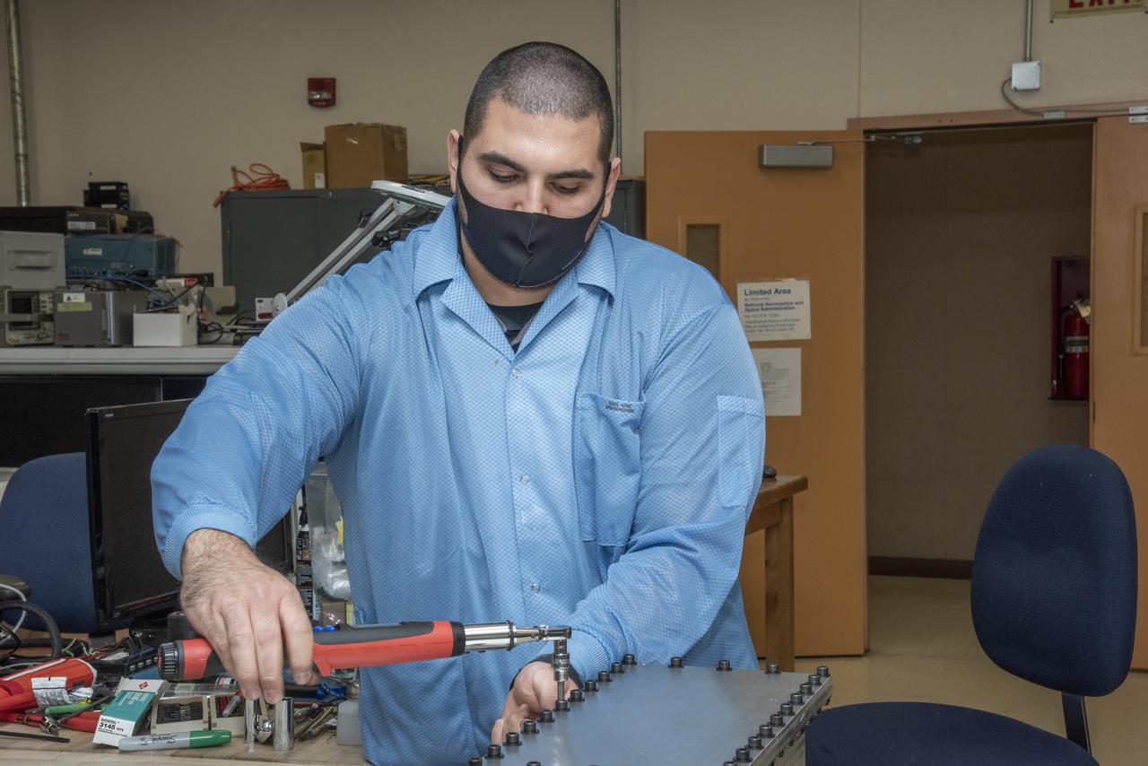 Bolts are torqued on a Compact Fiber Optic Sensing System unit, also known as a FOSS Rocket Box, which was developed at NASA's Armstrong Flight Research Center in California. NASA research engineer Jonathan Lopez works on the unit that is a new variant of aircraft technology that researchers have advanced to withstand the harsh environments of a rocket launch and space travel