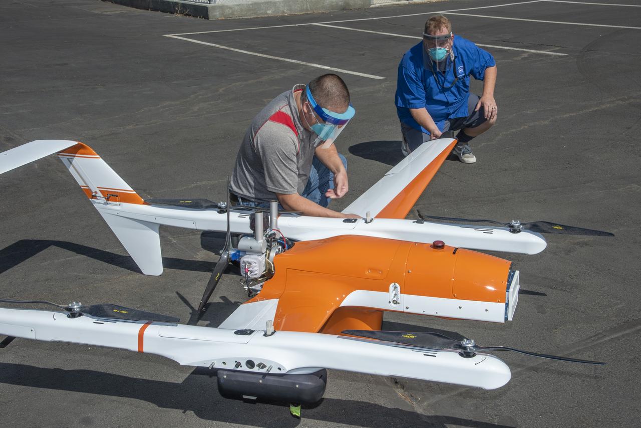 Derek Abramson and Robert Jensen install one of two wings on the Hybrid Quadrotor 90C (HQ-90) at NASA Armstrong Flight Research Center's Dale Reed Subscale Flight Research Lab in California on Oct. 1, 2020. This vertical lift and transition remotely piloted aircraft arrived in pieces packed in crates for the Resilient Autonomy project to test software in flight.