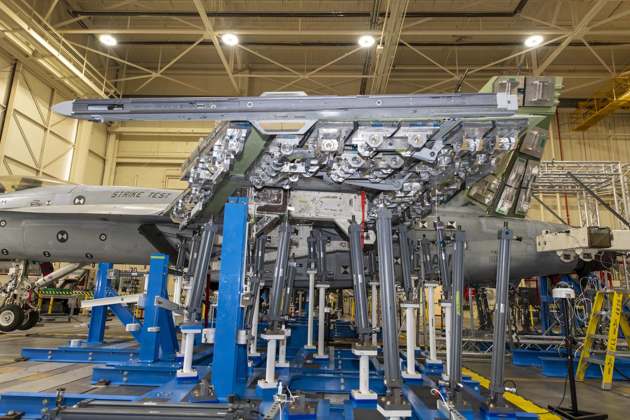 â€“ Installation of wing load test hardware is installed under the wing of a F/A-18E from the Naval Air Systems Command (NAVAIR) in Patuxent River, Maryland. The aircraft is in NASAâ€™s Armstrong Flight Research Center Flight Loads Laboratory in Edwards, California, for the centerâ€™s biggest load calibrations tests. This testing is needed before the aircraft can serve as a test vehicle for determining if it can safely manage maneuvers and proposed upgrades. 