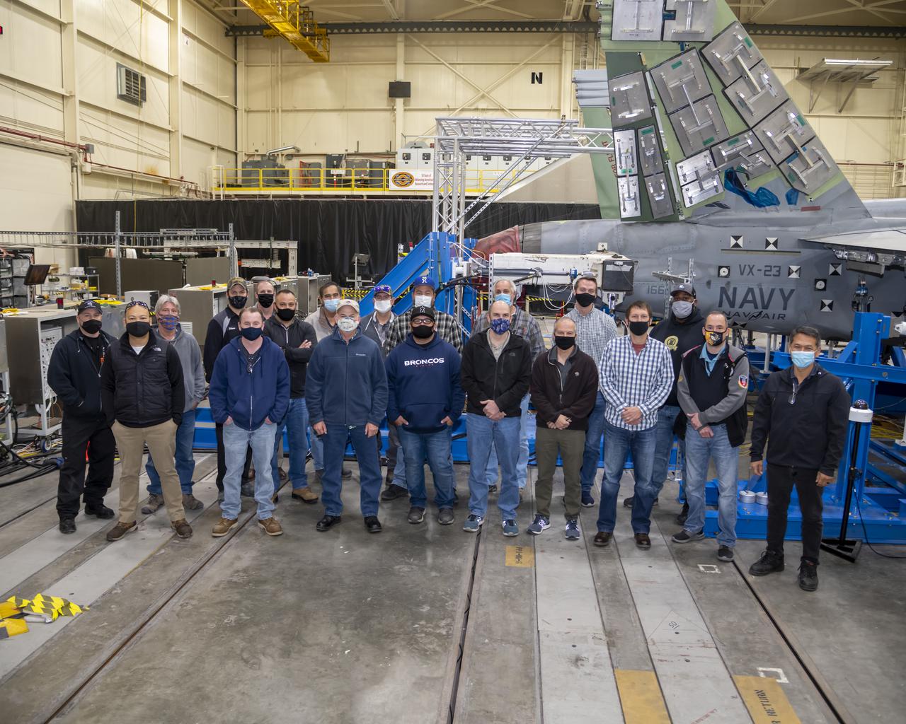 â€“ A team working on tests on a F/A-18E from the Naval Air Systems Command (NAVAIR) in Patuxent River, Maryland, stand by the aircraft. The F/A-18E is in NASAâ€™s Armstrong Flight Research Center Flight Loads Laboratory in Edwards, California, for the centerâ€™s biggest load calibrations tests. This testing is needed before the aircraft can serve as a test vehicle for determining if it can safely manage maneuvers and proposed upgrades. 