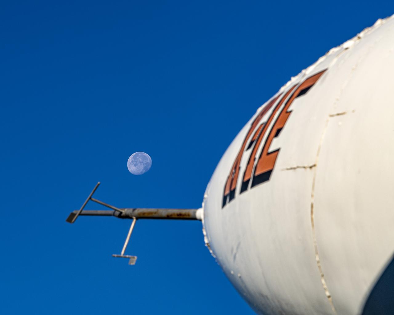 This is a forward-looking view of the X-1E that stands on static display in front of the main office building at NASA's Armstrong Flight Research Center in Edwards, California. Captured in the background of the image is the Waning Gibbous Moon on November 22, 2021. Visible off the nose of the X-1E is the air data probe with alpha and beta vanes which measured vertical and horizontal motion.