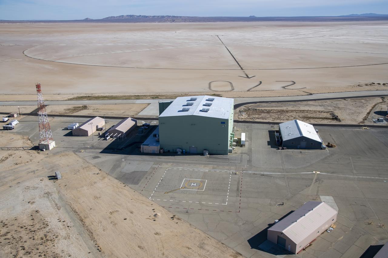 An aerial image taken by one of NASA's photographers during recent helicopter flights shows a view of the windward helipad and surrounding areas and structures that the Advanced Air Mobility National Campaign used during flight research at NASA's Armstrong Flight Research Center in Edwards, California. Part of the compass rose on the Edwards Air Force Base dry lakebed can also be seen.