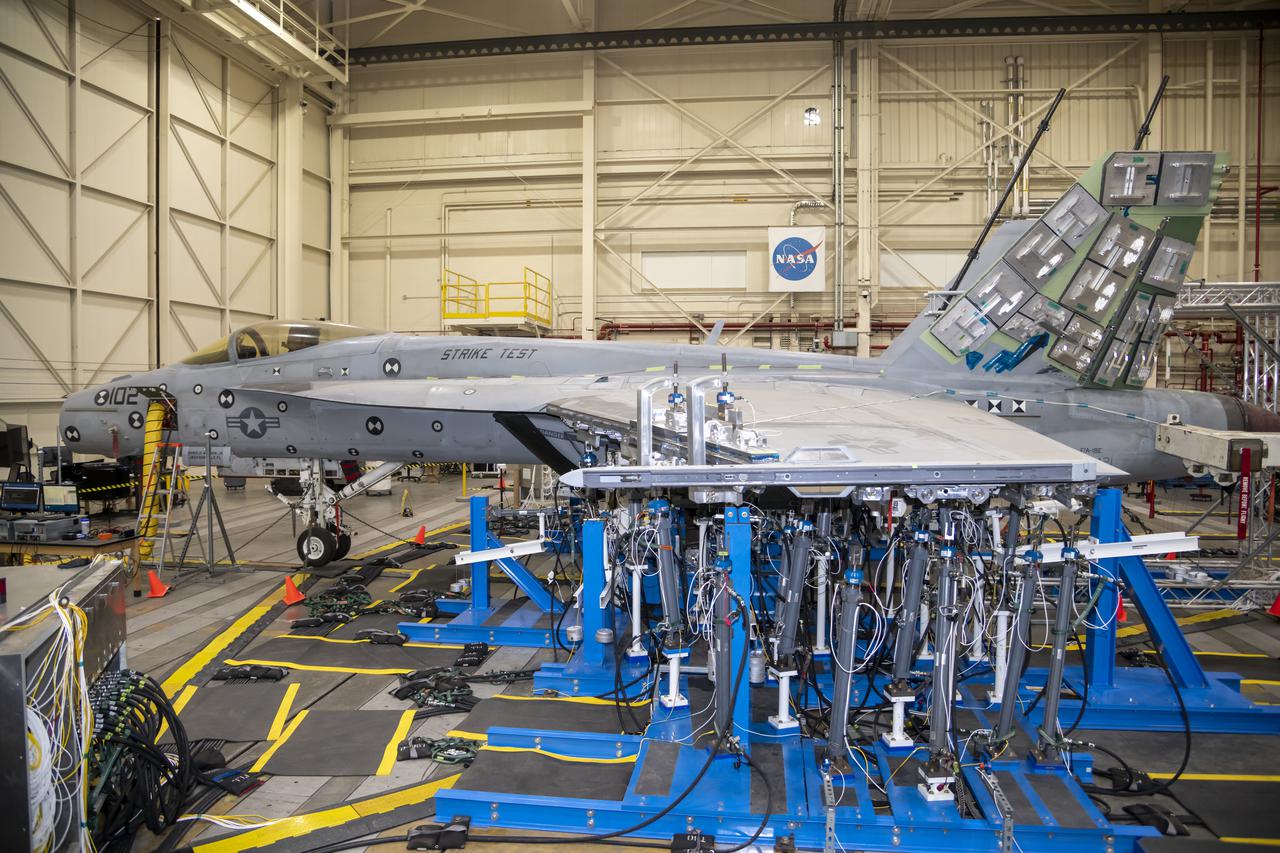 Left wing load hardware is setup for testing a F/A-18E from the Naval Air Systems Command (NAVAIR) in Patuxent River, Maryland. The aircraft is in NASA's Armstrong Flight Research Center Flight Loads Laboratory in Edwards, California, for the center's biggest load calibrations tests. This testing is needed before the aircraft can serve as a test vehicle for determining if it can safely manage maneuvers and proposed upgrades.