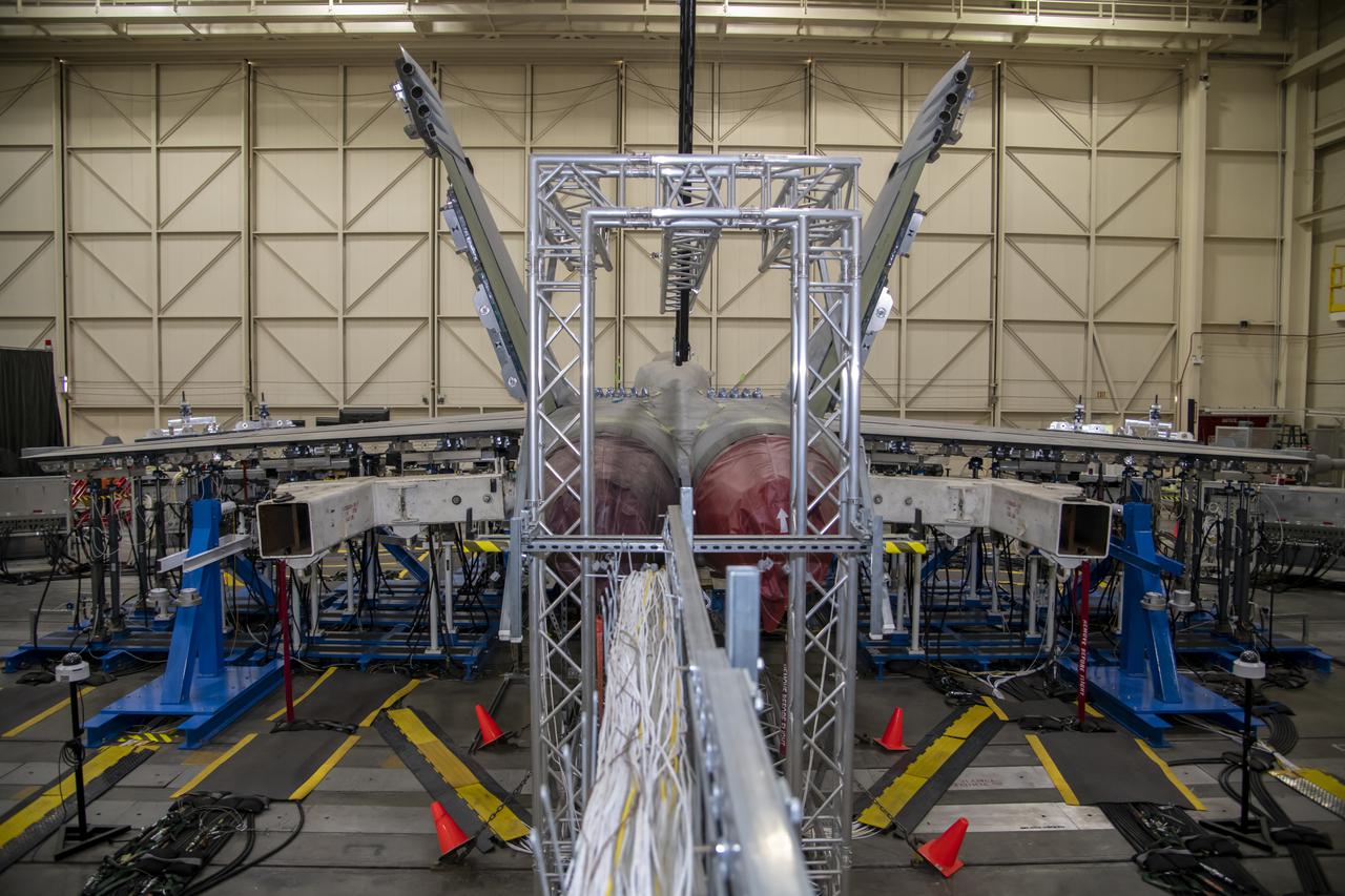 This rear view shows the wing loading test configuration and testing area of an F/A-18E from the Naval Air Systems Command (NAVAIR) in Patuxent River, Maryland. The aircraft is in NASA's Armstrong Flight Research Center Flight Loads Laboratory in Edwards, California, for the center's biggest load calibrations tests. This testing is needed before the aircraft can serve as a test vehicle for determining if it can safely manage maneuvers and proposed upgrades
